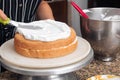 Female baker adding cream to a freshly-baked cake Royalty Free Stock Photo