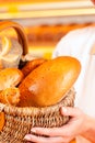 Female baker in bakery selling bread by basket Royalty Free Stock Photo