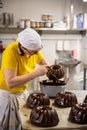 Female baker carefully adding chocolate to a freshly baked cake