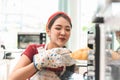 Female baker carrying some freshly baked bread out of the oven and smiling