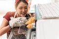 Female baker carrying some freshly baked bread out of the oven and smiling