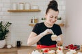 Female baker decorating cupcakes with colored berries.