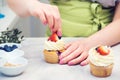 Female baker decorating tasty cupcake with berry. Pastry chef woman making creamy cakes