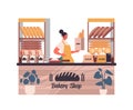 female baker holding bag with baguettes woman in uniform selling fresh bakery products in baking shop