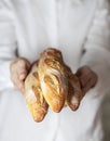 Female baker holds fresh baked French baguette. Homemade sourdough bread. Homemade food. Food preparation Royalty Free Stock Photo