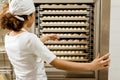 female baker pointing at dough inside of industrial oven Royalty Free Stock Photo