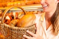 Female baker selling bread by basket in bakery Royalty Free Stock Photo