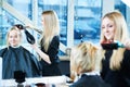 Female barber with hairdryer making male haircut.