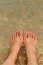 Female bare feet in sea water on sand beach Royalty Free Stock Photo