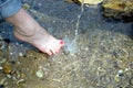 Female bare feet under rinning spring water closeup