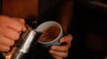 a woman pouring coffee into a cup with a metal coffee filterer