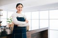 A female barista standing with a smile and confidence in front of the counter of the coffee shop. The woman leading in business