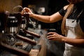 female barista turns on coffee machine that releases steam to make coffee drink