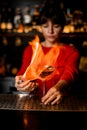 female barkeeper holds glass on bar counter and sets it on fire