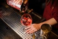 Female barman hands pouring sweet red alcoholic drink into a glass Royalty Free Stock Photo