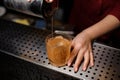 Female bartender hand pouring a fresh drink from shaker into a glass Royalty Free Stock Photo