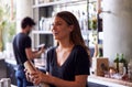 Female Bartender Mixing Cocktail In Shaker Behind Bar