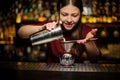 Female bartender pouring out a cocktail from the shaker through the sieve Royalty Free Stock Photo