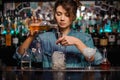 Female bartender pouring to the steel jigger an alcoholic drink