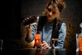 Female bartender pours tomato juice into glass with ice. Royalty Free Stock Photo