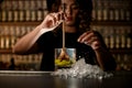 Female bartender pulls a muddler Turbo Swizzle Barta from a glass with water and lemon Royalty Free Stock Photo