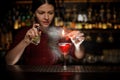 Female bartender spraying on the fire match above the cocktail