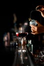 Female bartender spraying on fresh delicious cocktail for serving it on steel bar counter