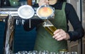 Female bartender tapping beer in bar, pouring from tap into the glass. Royalty Free Stock Photo