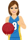 Female basketball player holding ball and showing thumbs up