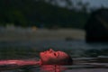 Woman enjoys serene swim in lagoon at dusk, peaceful floating, relaxation concept, tranquil water leisure activity