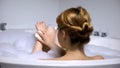 Female in bath washing body with cleansing soap, beauty procedure, back view