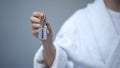 Female in bathrobe holding keys with Resort word, spa in hotel, all inclusive