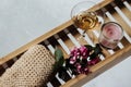 Female bathroom - romantic bath with natural pumice, glass of white wine, pink flowers and candle on shelf for a bathtub