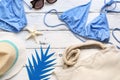 Female beach accessories-bikini swimsuit, hat, flip flops, sunglasses, bag on a white wooden background. Summer vacation concept. Royalty Free Stock Photo