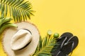 Female beach straw hat, sunglasses, flip flops and palm on yellow. Top view. Summer travel concept Royalty Free Stock Photo