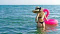 Female by beach. Young sexy woman in straw hat, bikini swimsuit, sunglasses with pink inflatable flamingo in blue ocean water Royalty Free Stock Photo