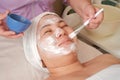 Female beautician applies a cleansing mask on the face with a brush in the Spa salon. Cosmetic procedure for facial rejuvenation Royalty Free Stock Photo