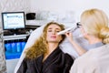 Female beautician does ultrasonic face cleaning and pulse therapy for pretty woman client sitting in a chair in a grey Royalty Free Stock Photo