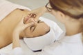 Female beautician doing facial massage for client lying in beauty center or spa. Royalty Free Stock Photo