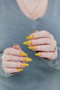 Female beautiful hand with long nails and a yellow nail polish Royalty Free Stock Photo