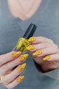 Female beautiful hand with long nails and a yellow nail polish Royalty Free Stock Photo