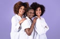 Three happy united black young women posing over purple background Royalty Free Stock Photo