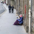 Female beggar sitting on the pavement holding a cup