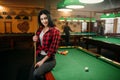 Female billiard player with cue poses at the table