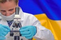 Woman with a microscope against Ukraine flag background. Medical technology and pharmaceutical research in Ukraine
