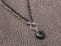 Female black heart shaped agate pendant with silver agate chain on spotted leather