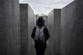 Female in black outfit and a backpack walking in the holocaust memorial in Berlin