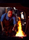 Female Blacksmith Heating Metalwork In Flames Of Forge Royalty Free Stock Photo