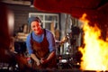 Female Blacksmith Heating Metalwork In Flames Of Forge Royalty Free Stock Photo