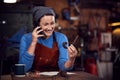 Female Blacksmith Working On Design In Forge Whilst Using Mobile Phone Royalty Free Stock Photo